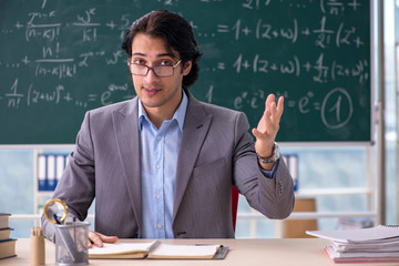 Young handsome math teacher in classroom