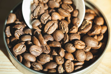 Close up Roasted coffee beans in container, spoonful of bean