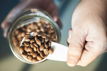 Close up Roasted coffee beans in container, spoonful of bean