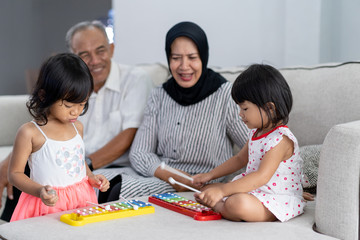 portrait of beautiful asian grandparent with their granddaughters in living room playing together