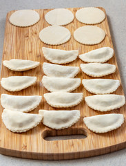 Pierogi laid out on a bread board ready for boiling