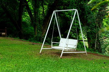 white swing bench chair under green tree