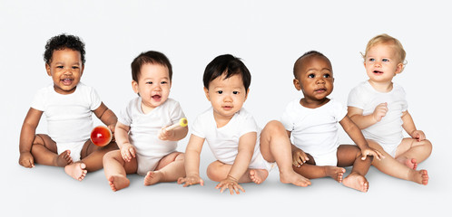 Diverse babies sitting on the floor - obrazy, fototapety, plakaty