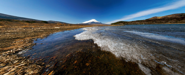 Beautiful Fuji mountain at cold lakeside with ice over the water and blue sky