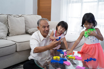 grandfather teaching his grandchildren about letter in livingroom at home. kids with grandparent