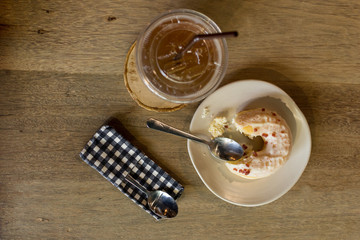 Lemon tea, bitten donuts and 2 spoons placed on a wooden table.