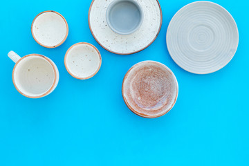 Kitchen concept. Crockery kit. Empty ceramic plates and mugs on blue background top view copy space