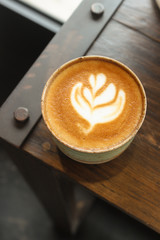 Latte coffee mug placed on a wooden table in a coffee shop