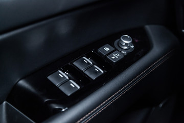 Сlose-up of the car  black interior:  the side door buttons: window adjustment buttons, door lock and other buttons.