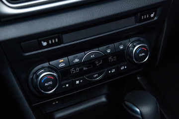 Сlose-up of the car  black interior:  dashboard, adjustment of the blower, air conditioner, player, accelerator handle and other buttons.