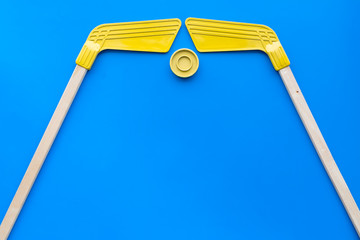 Ice hockey stick and puck on blue background top view copy space