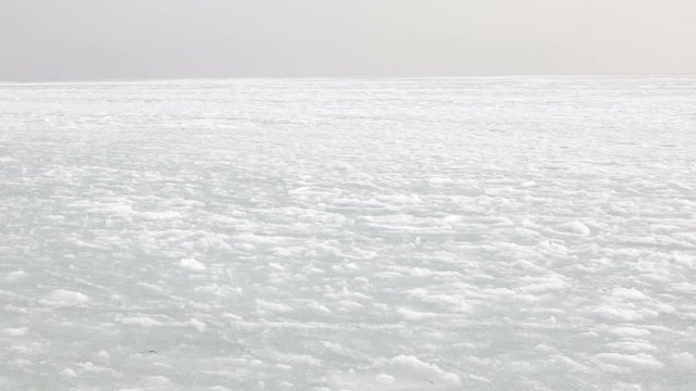 The background of white snow and spring thaw during the Far Eastern winter and the movement of ice and slush in the sea current against the background of an abstract landscape.