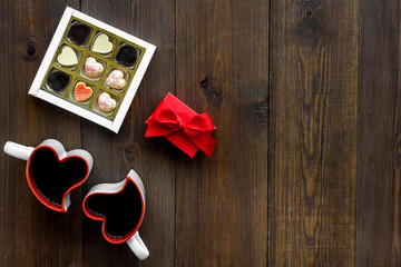 Dating on Valentine's day concept. Heart-shaped mugs and sweets on dark wooden background top view space for text