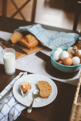 country breakfast on rustic home kitchen with farm eggs, butter, wholegrain bread and milk. Organic homemade food, easter concept.