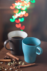 Hot coffee in a Cup and a coffee pot on the background of lights in the form of hearts