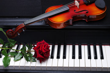 Fototapeta premium Red rose and violin on piano keyboard