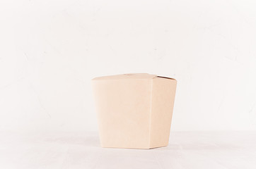 Blank disposable brown paper box for takeaway food on white wood shelf closeup, mockup food packaging for cafe, bar and restaurant.