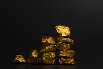 A pile of gold nuggets or gold ore on black background, precious stone or lump of golden stone,...