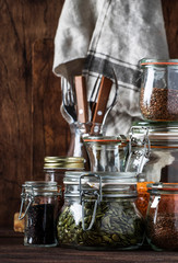 Stocks or set of cereals, pasta, groats, organic legumes and useful seeds in glass jars. Vegan source of protein and energy resources. Healthy vegetarian food. Domestic life scene. 