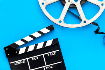 Filmings concept. Clapperboard and film stock on blue background top view copy space