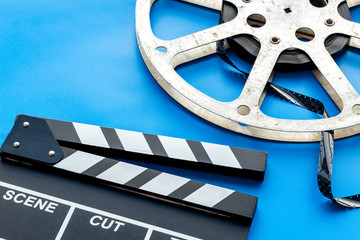 Cinema concept. Clapperboard, film stock on blue background copy space