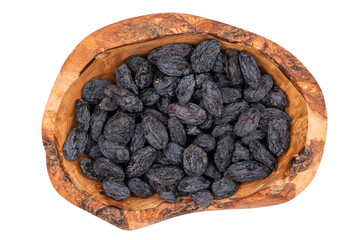 Black raisins in wooden bowl isolated on white. 
