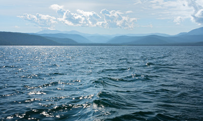 Lake Baikal. Chivyrkuy bay in summer. The view from the water of the mountains and hills in the haze. Natural blue background