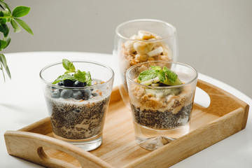 Fruits yogurt parfait with granola and chia seeds for healthy breakfast on wooden table