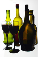 Two glasses of wine and wine bottles on a light background.