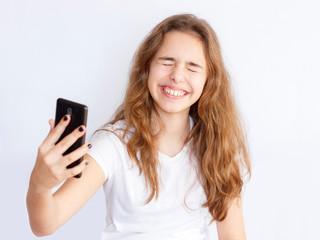 Fototapeta premium Pretty teenager girl with long hair makes selfie with funny laughing face