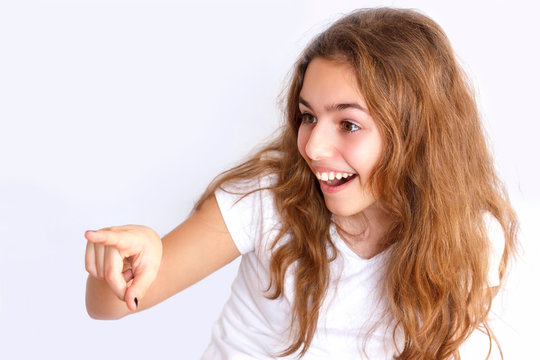 Teen girl laughs and points at something with a finger