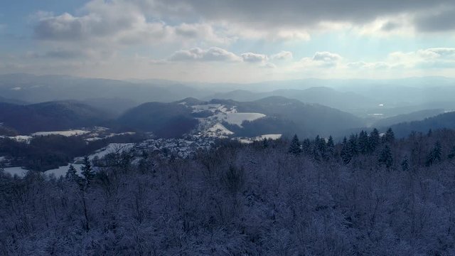 4K aerial ascending winter shot of a small European town between hills with church