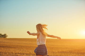 Cute young woman jumping in a wheat field.