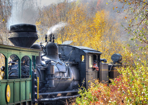 A vintage old train with thick smoke making its way through the forest in West Virginia. Shot near Cass, WV, USA.