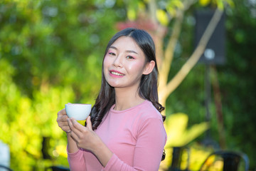 The girl is sipping coffee with pleasure at the coffee shop.