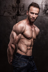 Fototapeta premium strong athletic man on dark grunge background