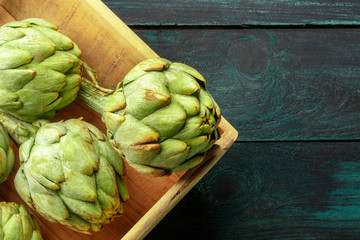 A closeup of a globe artichoke on a dark rustic wooden background with copy space