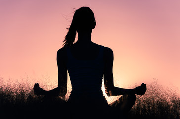 Fototapeta premium silhouette of young woman in yoga pose at sunset