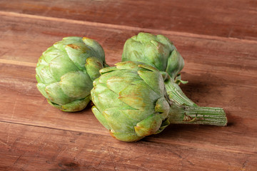 A closeup of a globe artichoke on a dark rustic wooden background with copy space