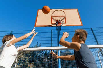 Streetball basketball game with two players, teenagers girl and boy with ball, outdoor city...