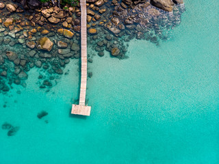 Island aerial view from drone, beach holiday vacation destination, transparent turquoise sea water with wooden pier and rocks, beautiful tropical paradise landscape, warm summer