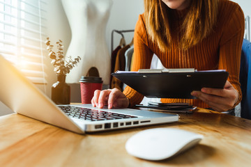  Fashion designer woman talking smart phone and using laptop with digital tablet computer in modern studio in morning light