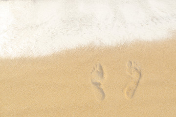 Texture background Footprints of human feet on the sand near the water on the beach. Copy Space.