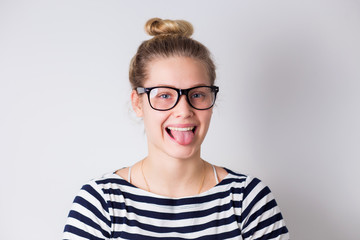 Funny cute young girl smiling winking showing tongue looking at camera over white background.