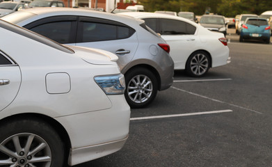 Plakat Closeup of back or rear side of white car and other cars parking in parking area in twilight evening.