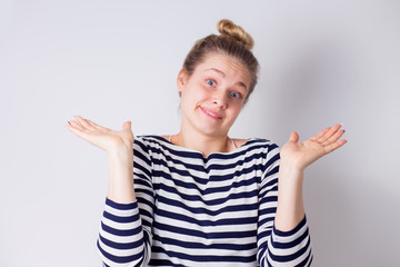 Portrait of confused and upset clumsy cute and silly girl shrugging and spread hands sideways in hopeless unaware gesture over white background