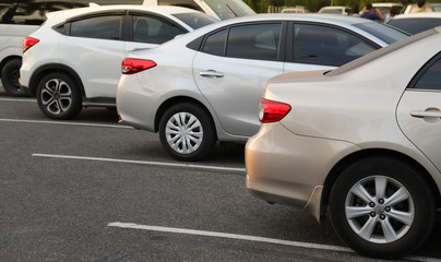 Closeup of back or rear side of golden car and other cars parking in parking area in twilight evening. 