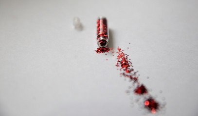 Red glitter bottle spilling out red  glitter. Copy space. 