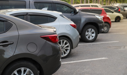 Closeup of back or rear side of brown car and other cars parking in parking area in twilight evening. 