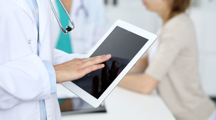 Doctor woman using tablet computer, close-up of hands at touch pad screen. Medicine and data concepts